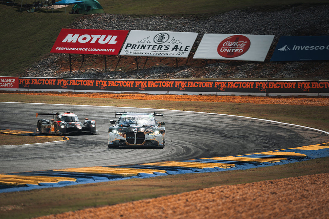 Two race cars barreling around the corner at Road Atlanta during the Petit Le Mans event.