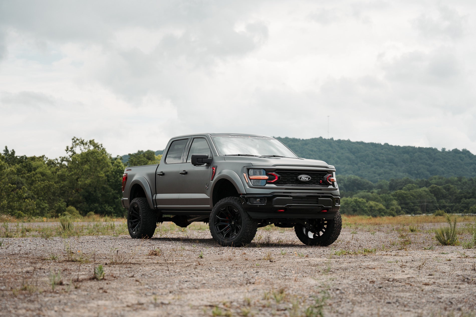 Lifted Black Widow F-150 parked off-road in a mountain scene.