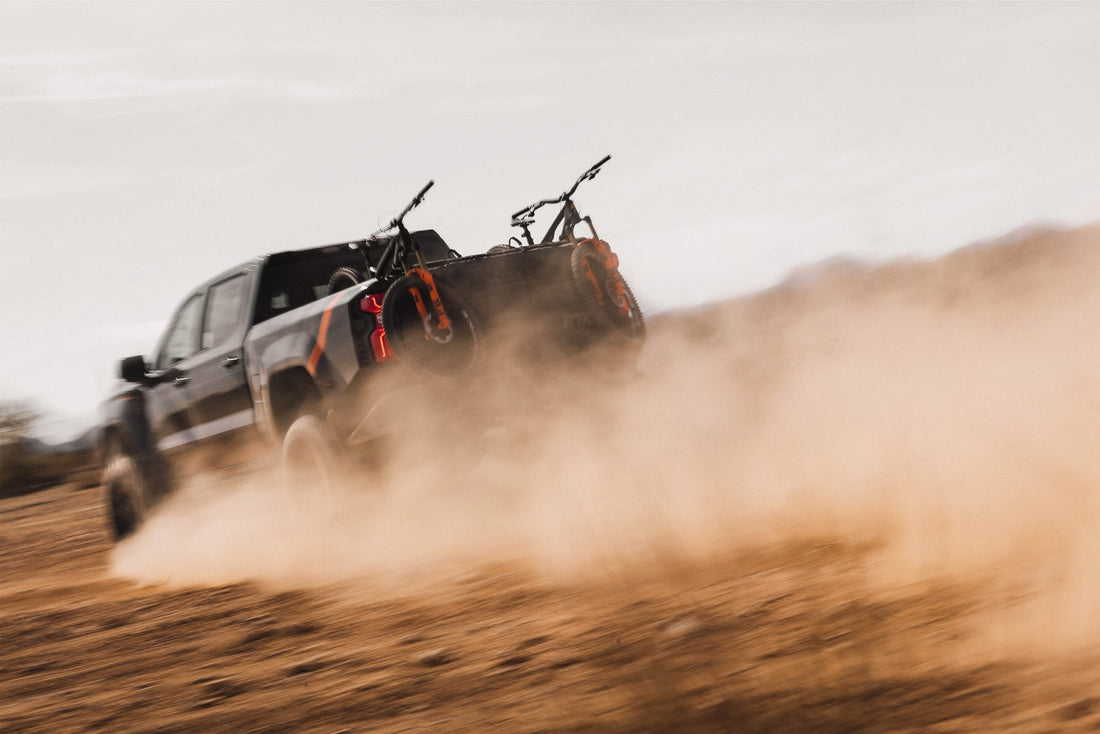 Fox Factory Truck kicking up dust in the desert with two mountain bikes in the truck bed.