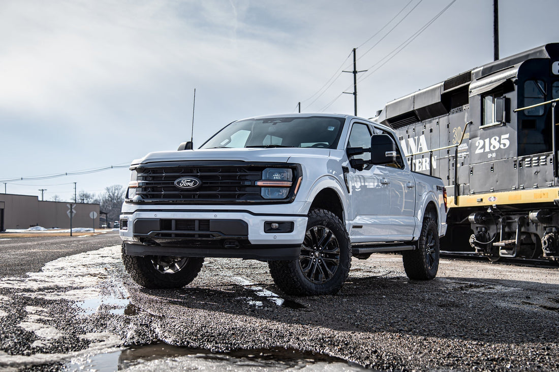 White lifted F-150 parked at angle in front of a train passing by.