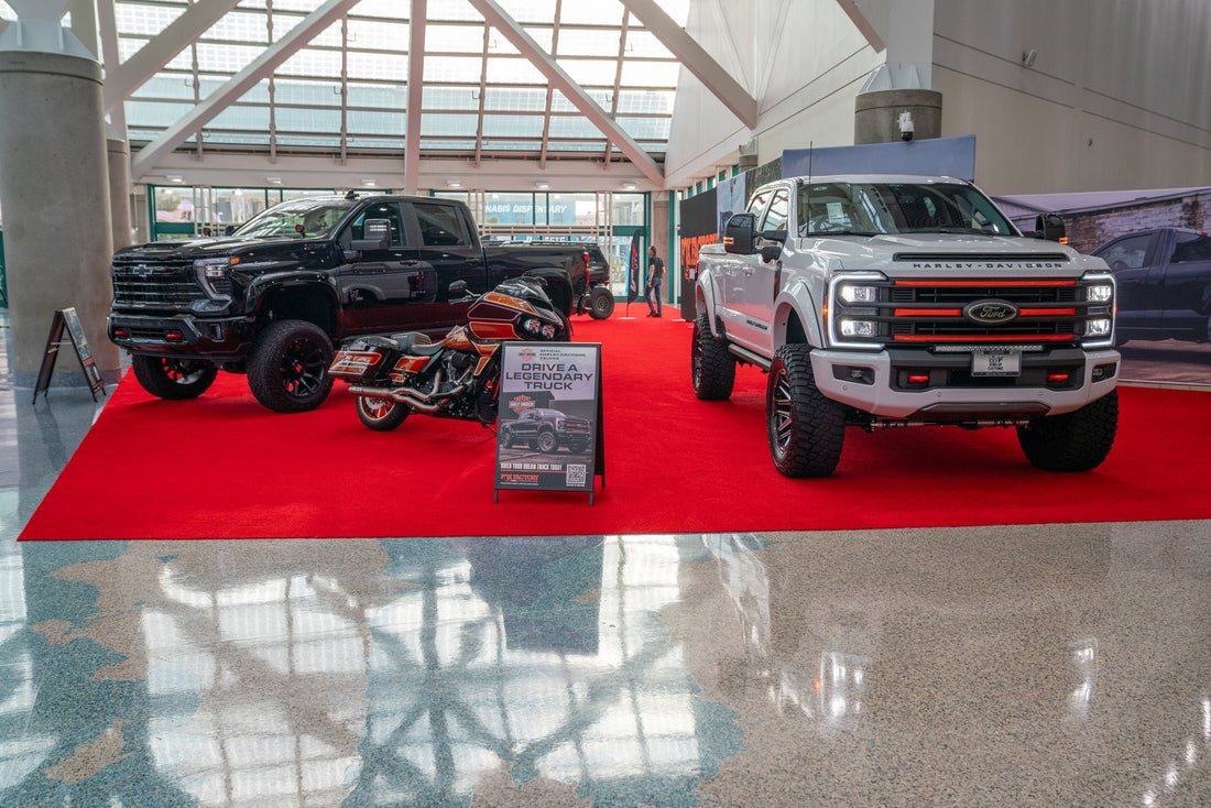 Harley-Davidson F-250 and Rocky Ridge Silverado parked at LA Auto show booth next to Harley-Davidson motorcycle